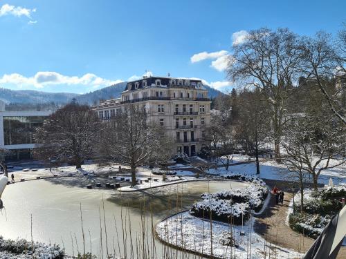 un bâtiment dans un parc avec de la neige au sol dans l'établissement Hotel Löhr, à Baden-Baden