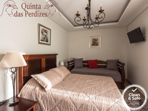 um quarto com uma cama e um sofá em Quinta das Perdizes em Ponta Delgada