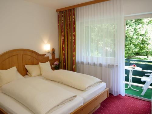 a bedroom with a bed and a window with a patio at Hotel Garni Christl in Bad Griesbach