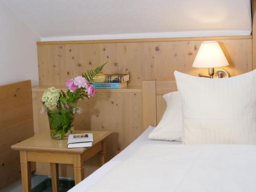 a bedroom with a bed and a vase of flowers on a table at Hotel Garni Christl in Bad Griesbach