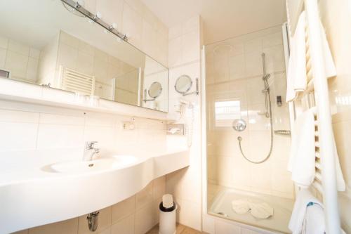 La salle de bains blanche est pourvue d'un lavabo et d'une douche. dans l'établissement Hotel Garni Christl, à Bad Griesbach im Rottal