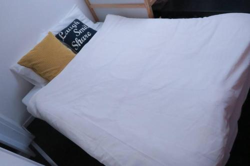 a bed with white sheets and a sign on it at A's Guest Room 303 in Osaka