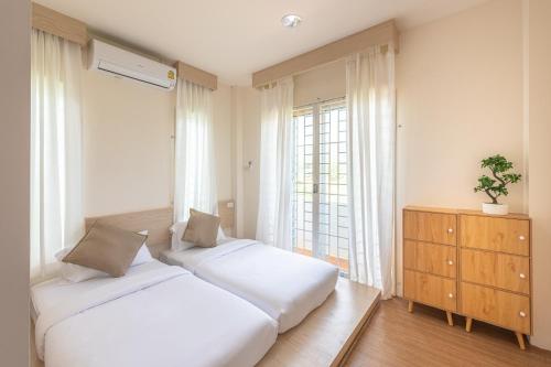 1 dormitorio con 2 camas y ventana en Hoteru House Ranong 1 - โฮเตรุ เฮ้าส์ ระนอง, en Ranong