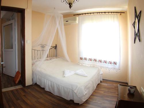 a bedroom with a white bed with a window at Tuncay Pension in Selcuk