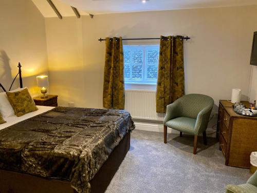 a bedroom with a bed and a chair and a window at White Hart Hotel in Dorchester on Thames