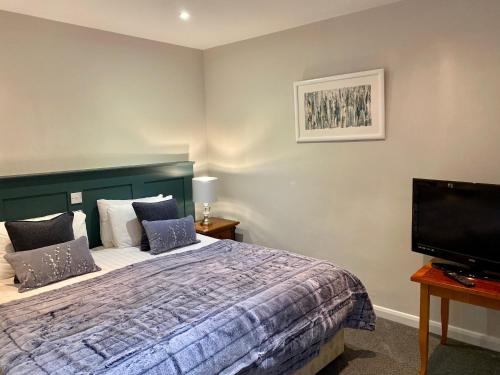 a bedroom with a bed and a flat screen tv at White Hart Hotel in Dorchester on Thames
