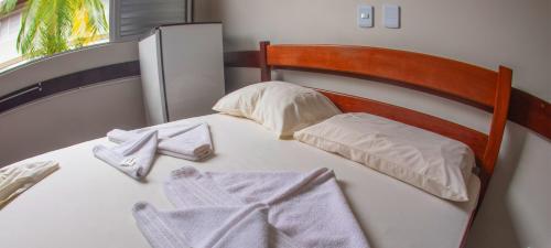 a bed with two towels on top of it at Pousada Pontal de Guaratuba in Guaratuba