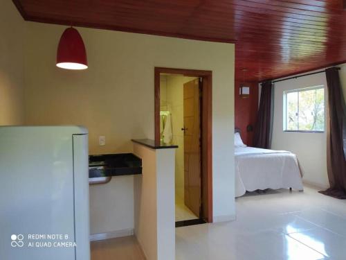 a room with a bedroom with a bed and a refrigerator at Suites Cantinho de MInas in Lavras Novas