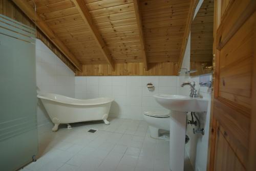 a bathroom with a tub and a toilet and a sink at Sunny Day Jeju in Seogwipo