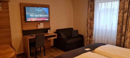 a hotel room with a bed and a chair and a television at Akzent Hotel Köhler in Gießen