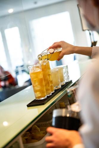 a person holding a tray of drinks on a counter at Nymindegab Kro in Nørre Nebel