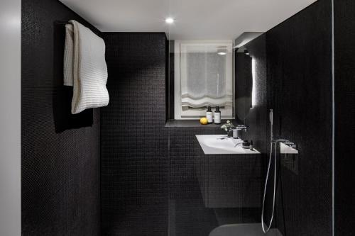 a black bathroom with a sink and a mirror at La Colombe Boutique Hotel in Zug