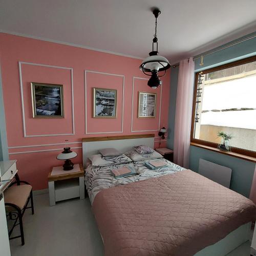 a bedroom with a bed and a pink wall at Villa Eva & Lilou Pod Rysianką in Żabnica
