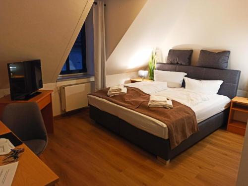 a bedroom with a large bed and a television at Stadthotel Deggendorf in Deggendorf
