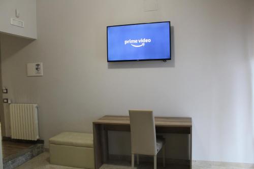 a television on a wall with a table and a chair at B&B D'Amari Affittacamere in Palermo