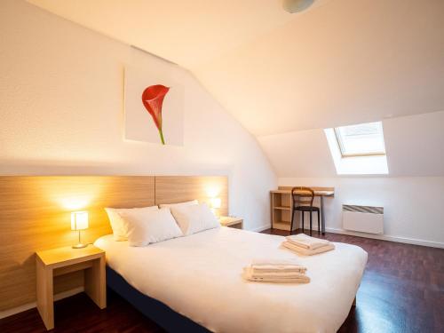 ein Schlafzimmer mit einem großen weißen Bett im Dachgeschoss in der Unterkunft Residhotel St Etienne Centre in Saint-Étienne