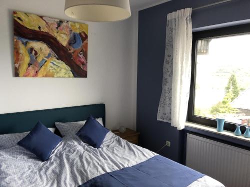 a bedroom with a bed with blue pillows and a window at Ferienhaus Schöner Maarblick in Schalkenmehren