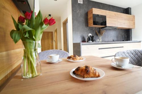 a table with two plates of food and a vase of flowers at Beskidzka9 & Free Sauna in Szczyrk