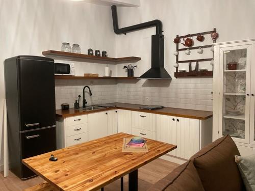 a kitchen with a wooden table and a black refrigerator at BORBOLETA AZUL ALOJAMIENTO TURISTICO in Villarreal