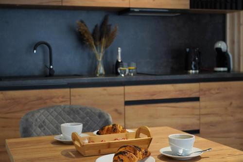 a table with a tray of pastries and cups on it at Beskidzka9 & Free Sauna in Szczyrk