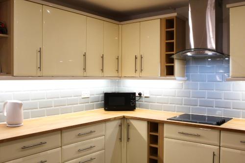 una cocina con armarios blancos y azulejos azules en The Duffryn en Mountain Ash