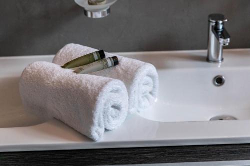 a white bathroom sink with towels on it at Hotel Ô Château in Hayange