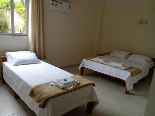 two beds in a room with towels on them at Riachuelo Hotel in Resende