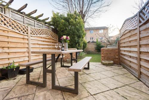 un patio con una valla de madera, una mesa y bancos en Second Nest Hampton Street, en Londres