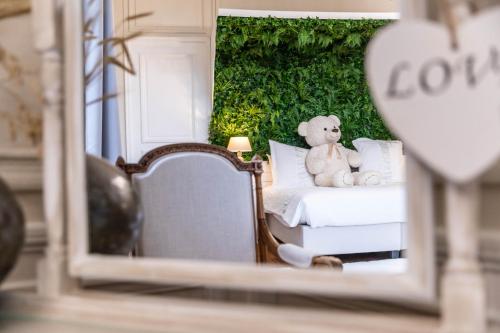 a teddy bear sitting on a bed in a mirror at Hotel Ô Château in Hayange