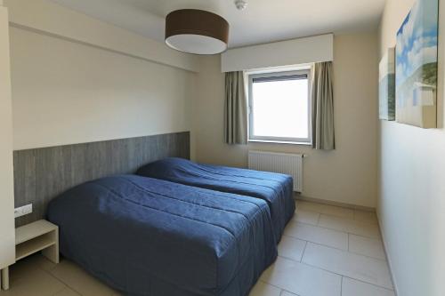 a bedroom with a blue bed and a window at Vayamundo Oostende - Apartments in Ostend