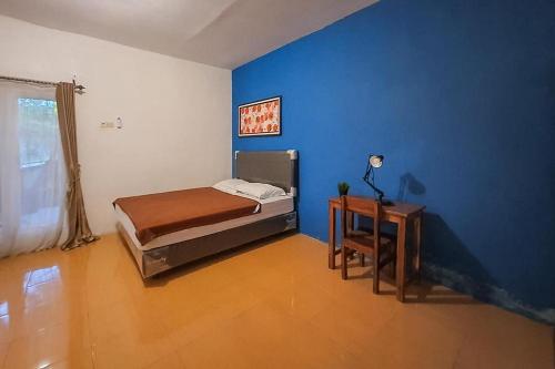 - une chambre avec un lit et un mur bleu dans l'établissement Syafa Homestay Syariah Mitra RedDoorz, à Jembel