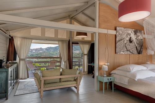 um quarto com uma cama, uma cadeira e janelas em Be Vedetta - Relais & Glamping - Adult Only em Scarlino