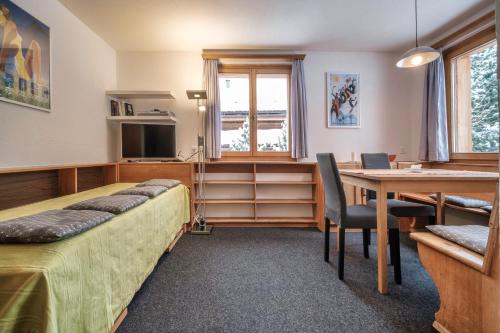 a bedroom with a bed and a desk and a table at Chalet Höckli Wohnung 2. in Arosa