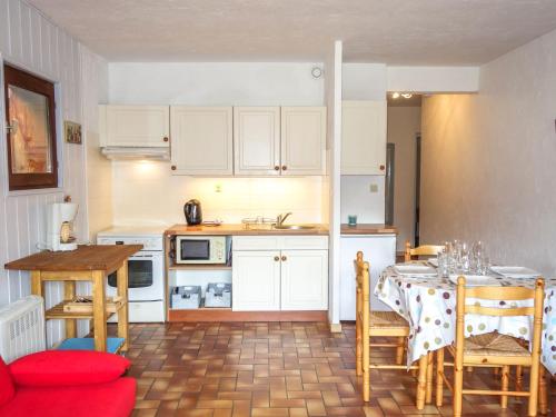 サン・ジェルヴェ・レ・バンにあるApartment Les Grets-7 by Interhomeの白いキャビネット、テーブルと椅子付きのキッチンが備わります。