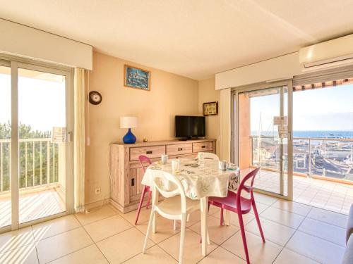 ein Esszimmer mit einem Tisch, Stühlen und einem TV in der Unterkunft Apartment Le Capitole-2 by Interhome in Fréjus