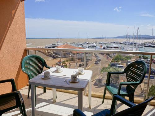 einen Tisch und Stühle auf einem Balkon mit Blick auf den Yachthafen in der Unterkunft Apartment Le Capitole-2 by Interhome in Fréjus