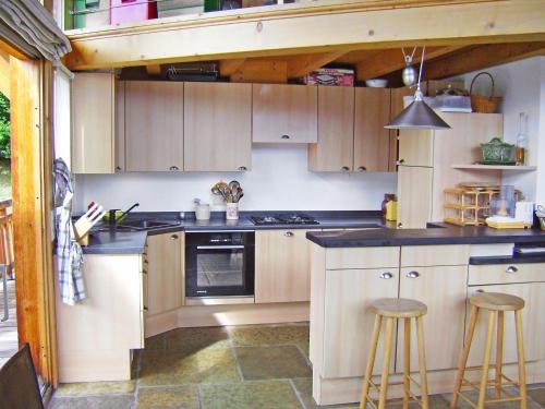 een keuken met houten kasten, een fornuis en krukken bij Chalet L'Epachat by Interhome in Mémontel