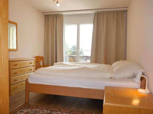a bedroom with a bed with a window and a table at Apartment Allod Park Haus C 604 by Interhome in Davos