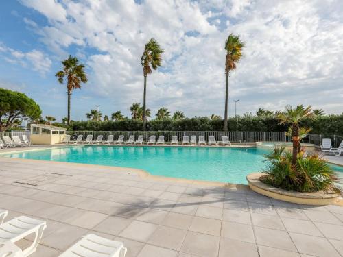 a swimming pool with chairs and palm trees at Apartment Cap Hermes-2 by Interhome in Fréjus