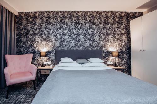 a bedroom with a bed and a pink chair at Miejsca noclegowe i Restauracja Kamiński in Kępno