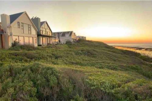 a house on a hill next to the ocean at Baby Whale Bliss - Beachfront House in Witsand