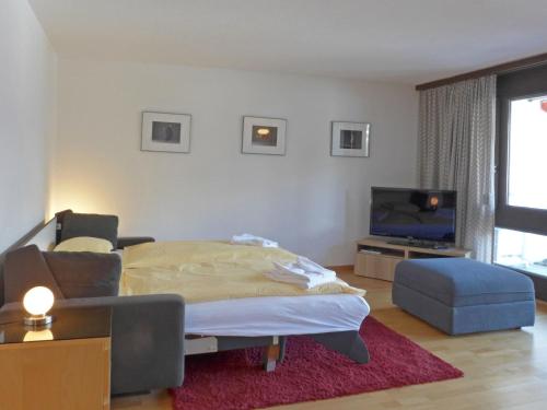 a living room with a bed and a tv at Studio Krokus by Interhome in Wengen