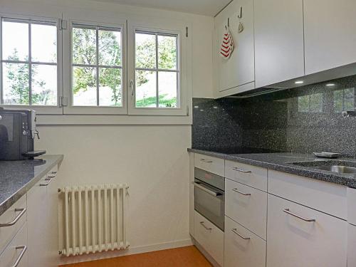 ヴェンゲンにあるApartment Drei Tannen by Interhomeのキッチン(白いキャビネット、ラジエーター、窓付)