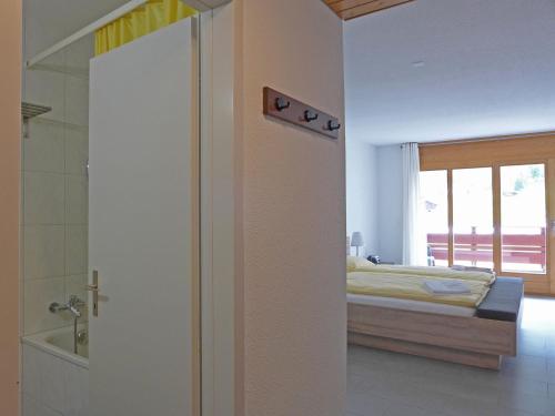 a bedroom with a bed and a bathroom with a shower at Apartment Eiger Residence Apt-H by Interhome in Wengen