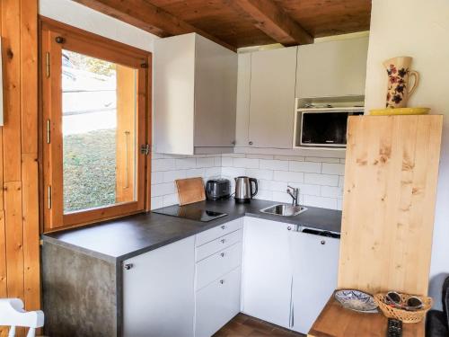une cuisine avec des armoires blanches, un évier et une fenêtre dans l'établissement Apartment Les Grets-9 by Interhome, à Saint-Gervais-les-Bains
