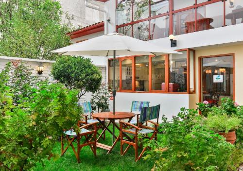 a table and chairs with an umbrella in a garden at Laramani Hotel Boutique in Cusco