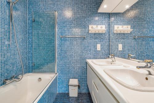 uma casa de banho em azulejos azuis com um lavatório e uma banheira em Ster Der Zee-Fijn app met uitgestrekt zicht op zee em Koksijde