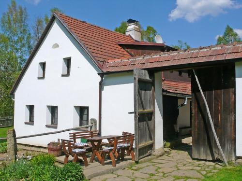 a white building with benches and a table and chairs at Holiday Home Benešov nad Černou by Interhome in Dluhoště