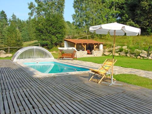 a swimming pool with an umbrella and a chair at Holiday Home Benešov nad Černou by Interhome in Dluhoště