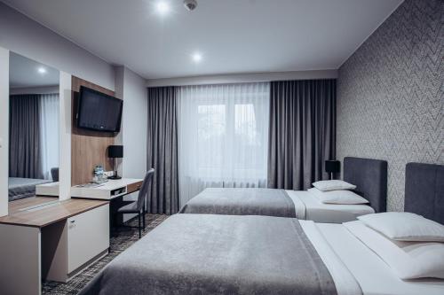 a hotel room with two beds and a desk and a television at Miejsca noclegowe i Restauracja Kamiński in Kępno